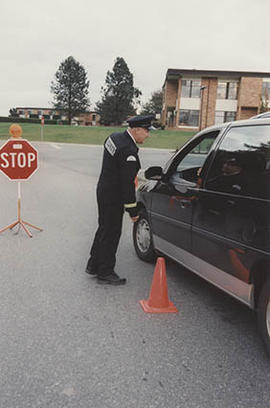 Unidentified security staff member standing next to a stopped vehicle