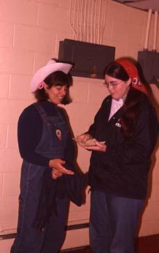 Students dressed in overalls speaking in a corridor.