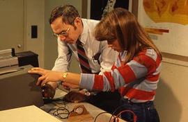 Unidentified faculty member assisting a student with an experiment in class.