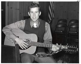 A male member of the TJC Tour Group posing with a guitar