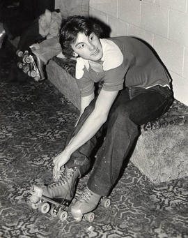 Student lacing up roller skates at a roller rink