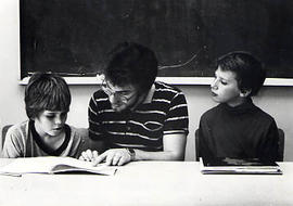 Student reading with two children during Outreach