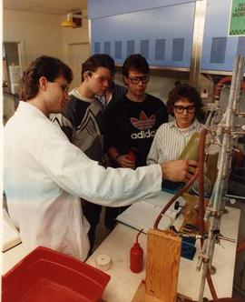 Graduate and students discussing a chemistry experiment.