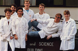 Mixed group of seven students in white lab coats