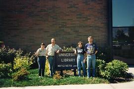 Library staff and faculty posing outside by the library sign