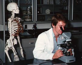 Male student using a microscope