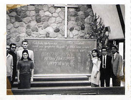 International students posing at the front of the chapel with a chalkboard