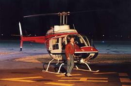 Bob Garnhum posing beside a helicopter