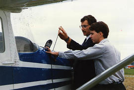 Aviation instructor checking the oil with a student