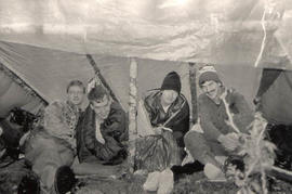 Four aviation students huddled under a lean-to